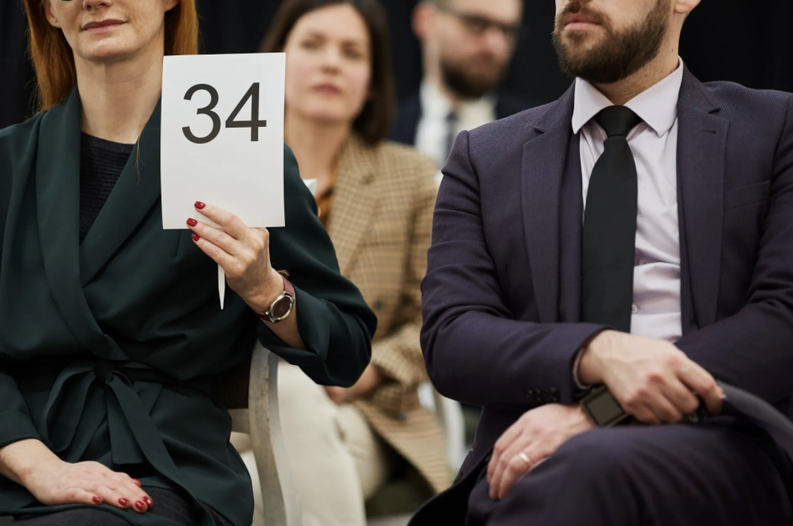 Lady holding up a number to bid at a live business liquidation auction