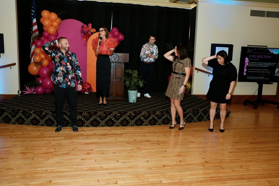 Courtney Buman leading a fun crowd moment on stage during a live benefit auction