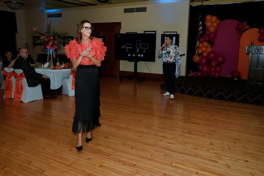 Courtney Buman working the room during a fundraising gala while Travis Buman calls from the floor