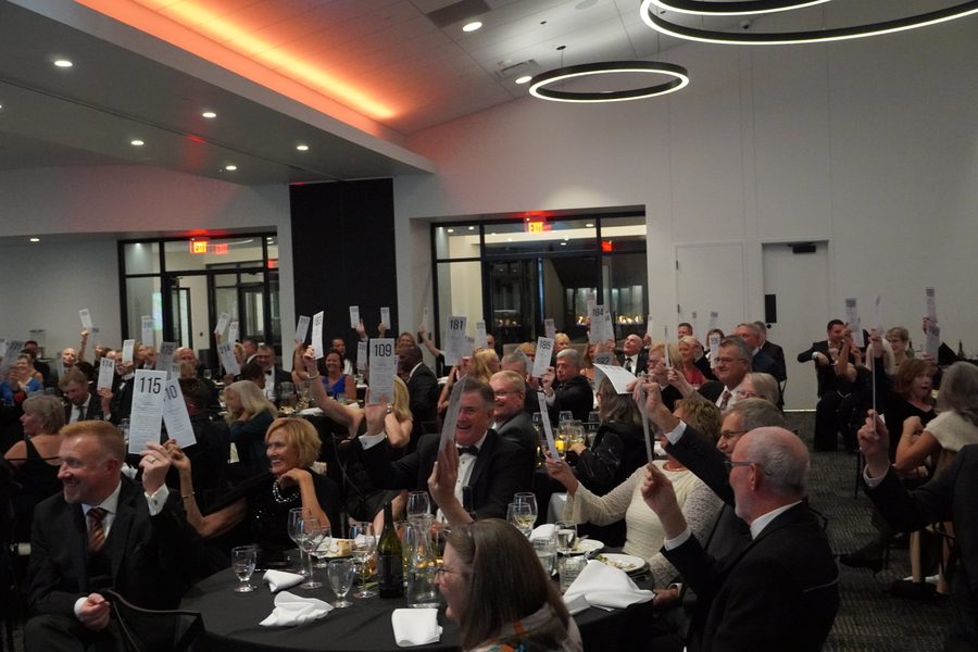 Gala guests raising their bid cards during a charity auction